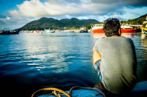 Homem olhando para água como se tivesse de férias