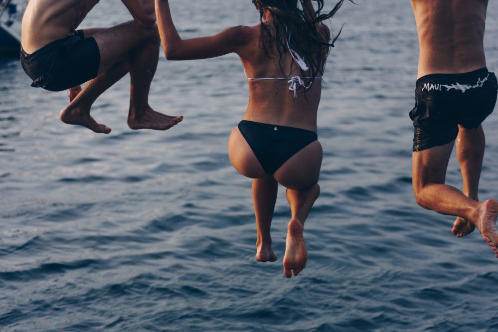 Pessoas com roupa de banho pulando na agua