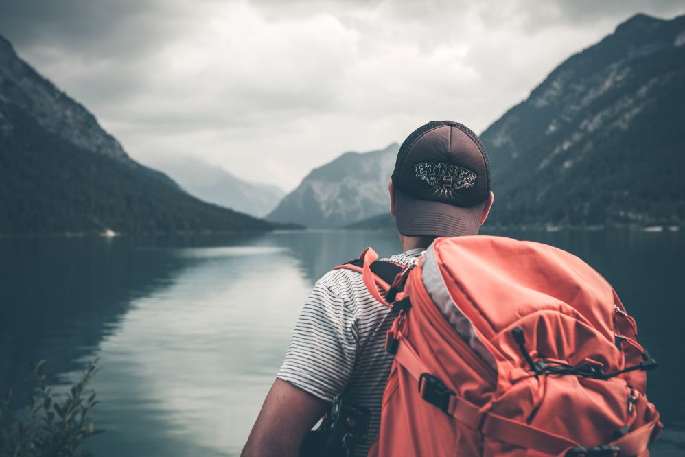 Homem de costas com mochila e olhando paisagem